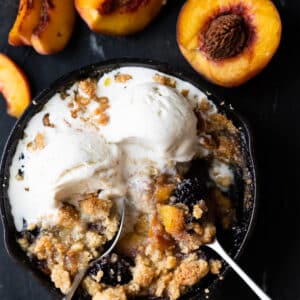 Keto peach and blackberry crisp baked in a skillet and served with two scoops of vanilla ice cream