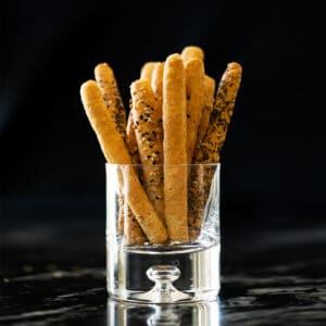 Keto breadsticks in a glass with a black background
