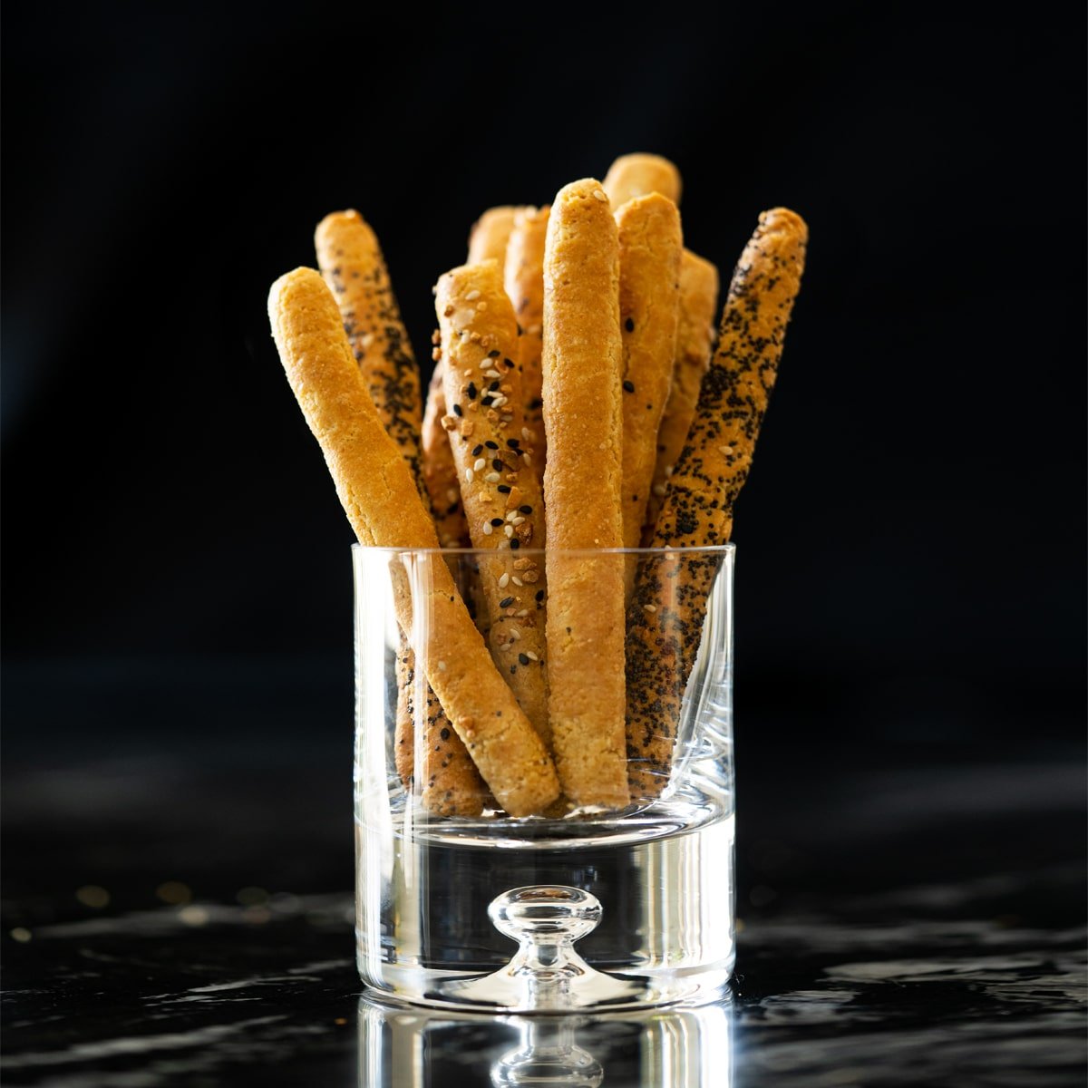Keto breadsticks in a glass with a black background