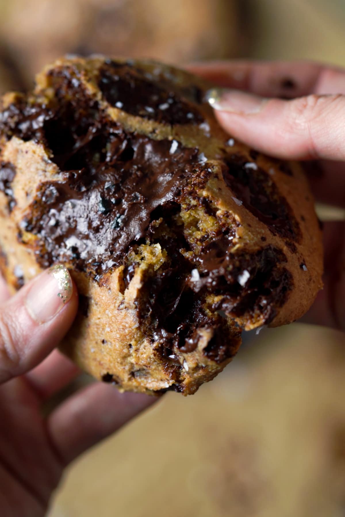 Halving a brown butter keto chocolate chip cookie showing the gooey chocolate
