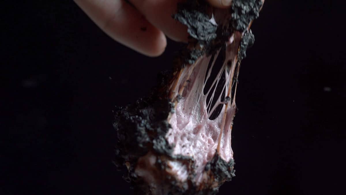 Pulling apart a charred maple grape marshmallow showing its sticky texture