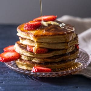 A stack of keto pancakes with sugar free syrup and strawberry slices