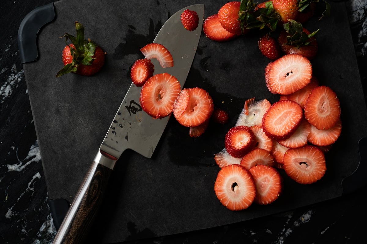 Slicing strawberries on a black cutting board