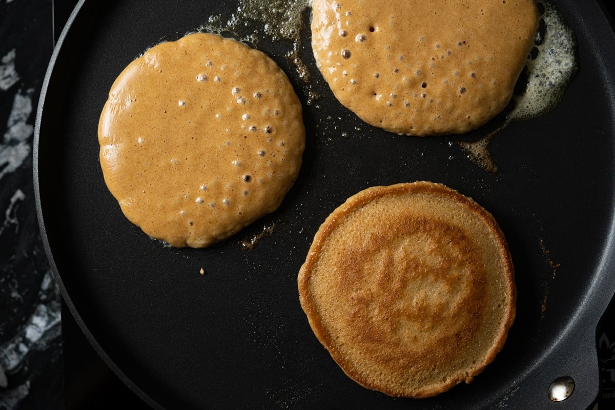 Cooking flourless keto pancakes until bubbly and lightly golden