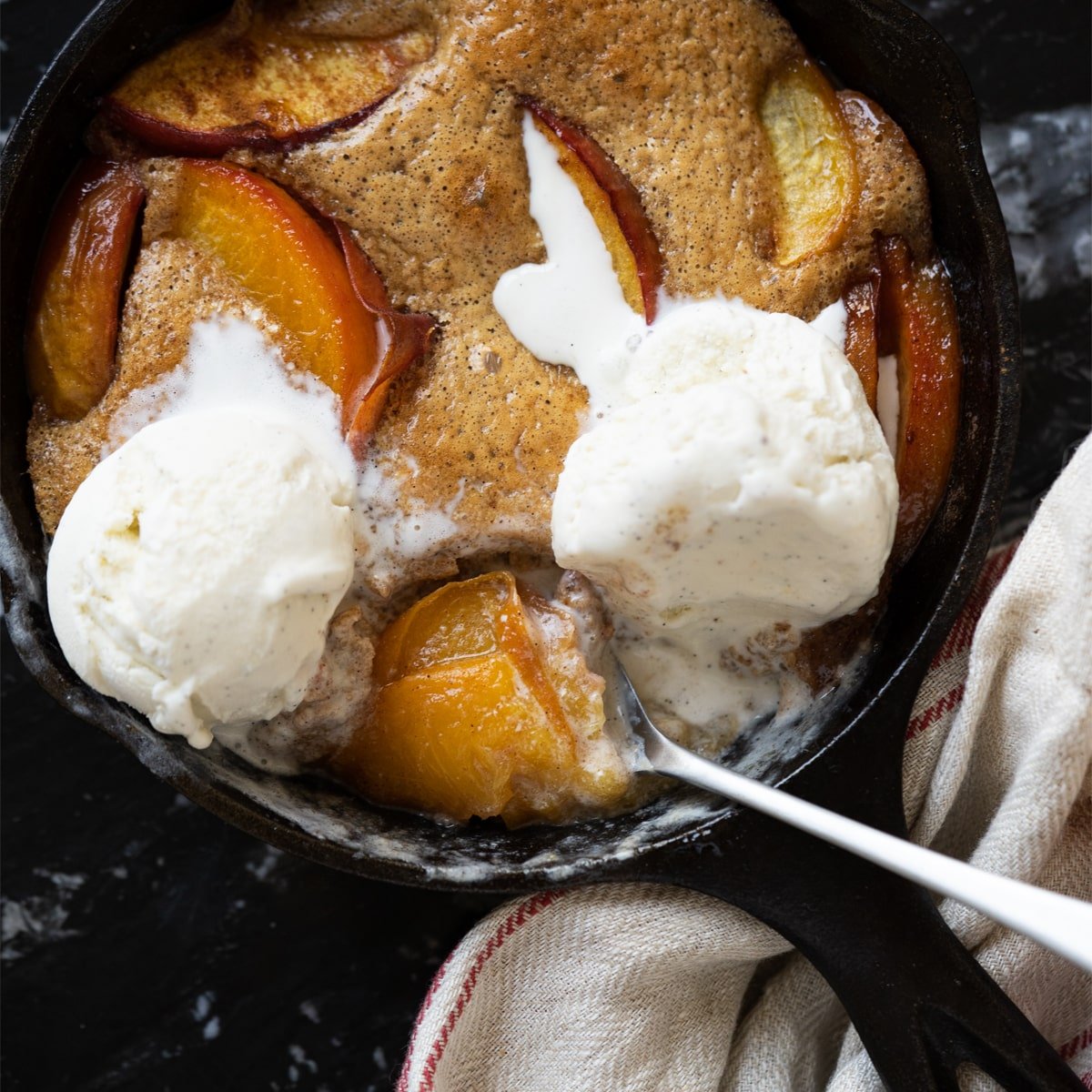 Keto peach cobbler with a flourless cake like topping and vanilla ice cream