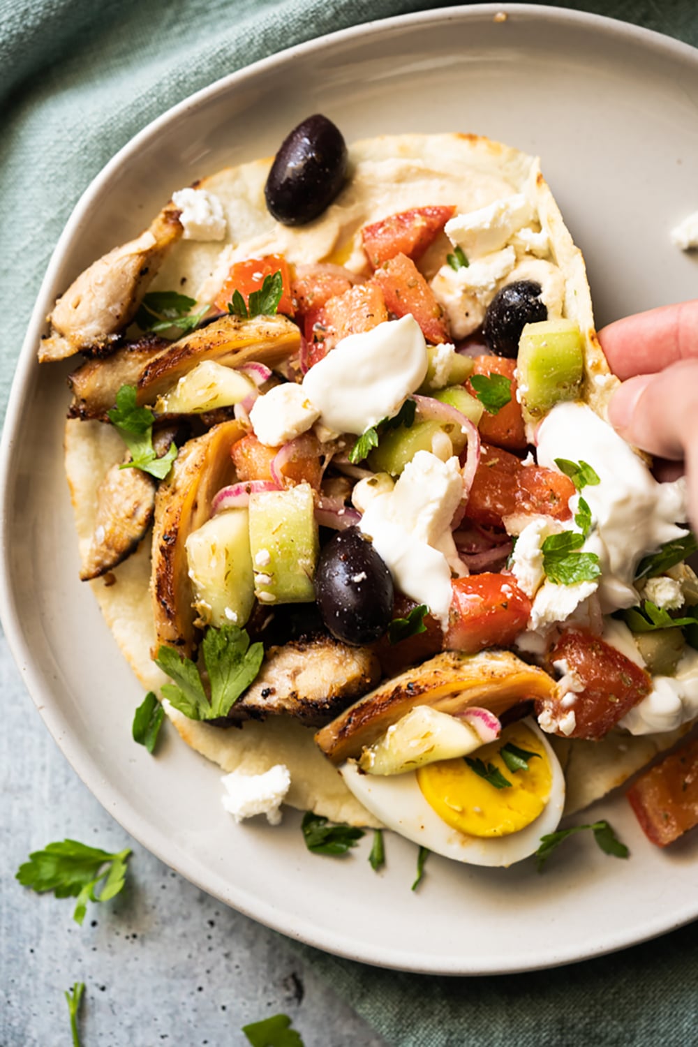 Folding a keto chicken wrap with tomatoes, eggs, cucumber, olives and feta cheese