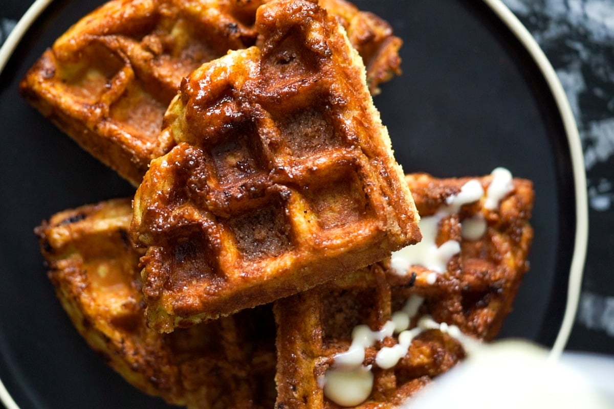 Drizzling the sugar free glaze onto the low carb cinnamon roll waffles with yeast