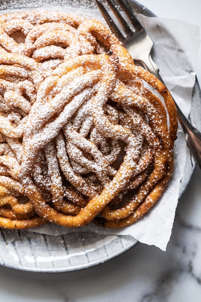 Keto funnel cakes with powdered 'sugar', on a plate with a fork