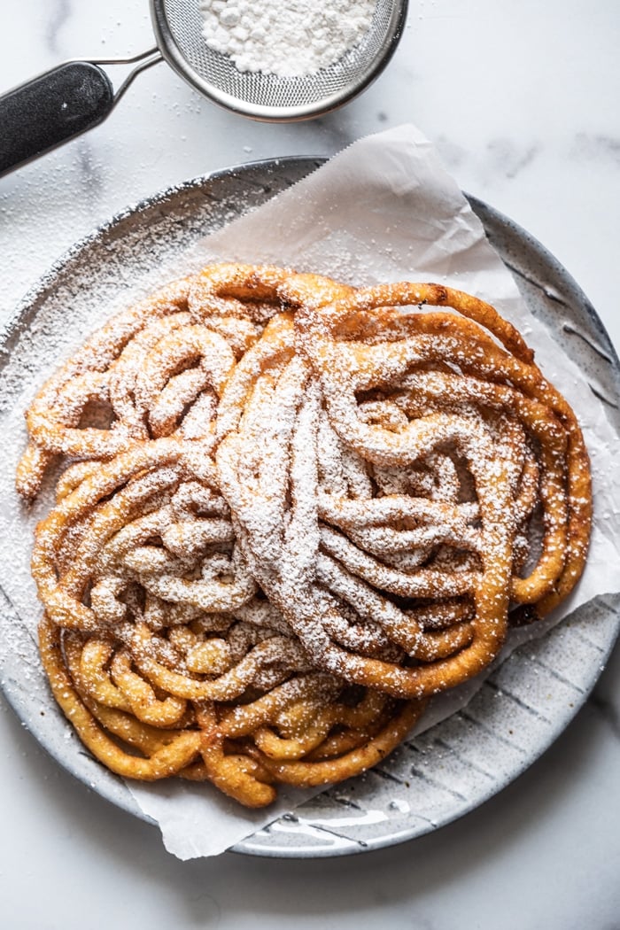 Overhead shot keto funnel cakes with powdered sugar sieve