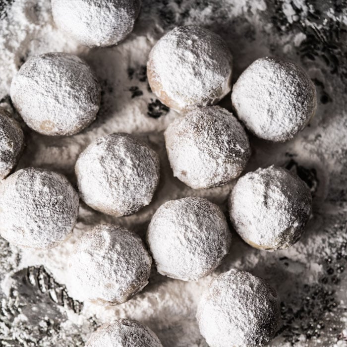 Rolling keto snowball cookies in powdered sweetener