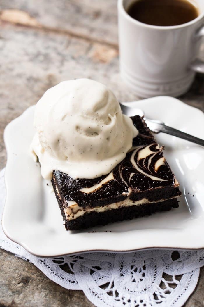 A slice of keto cheesecake brownie with a scoop of vanilla ice cream