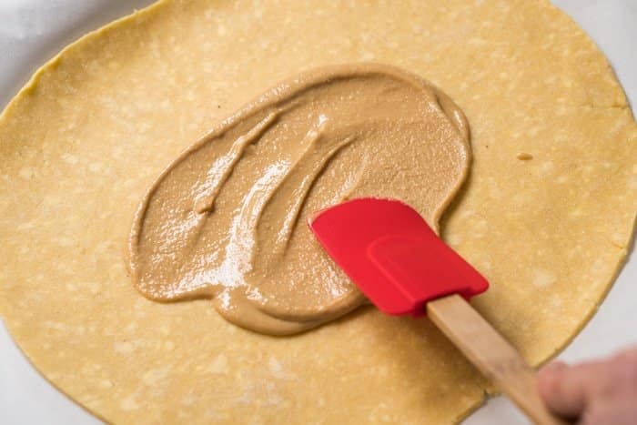 Spreading peanut butter onto keto pie crust