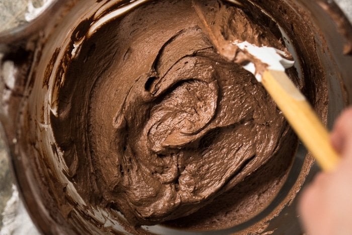 A bowl of keto chocolate buttercream frosting with a spatula