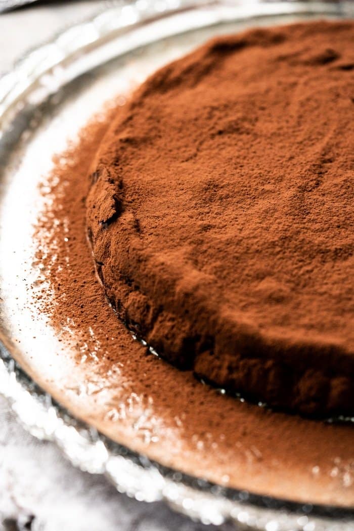 Uncut keto flourless chocolate cake dusted with cocoa