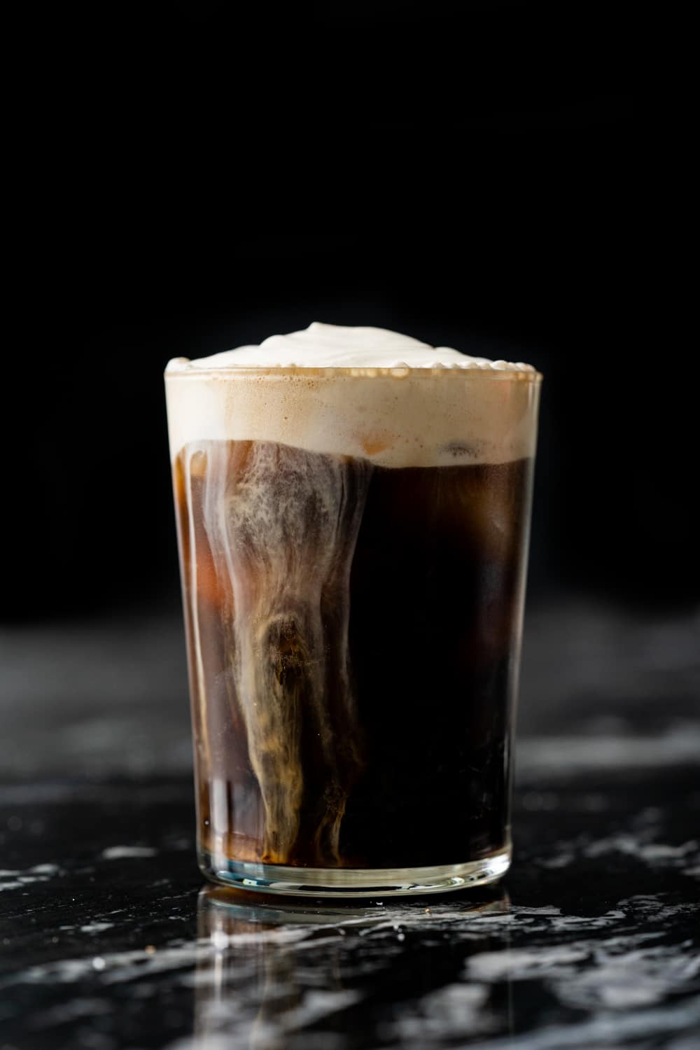 A homemade salted caramel cream cold brew on a black marble table