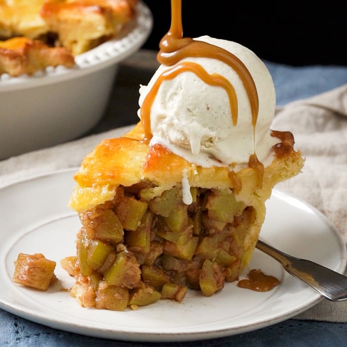 A slice of keto apple pie with a scoop of vanilla ice cream and caramel sauce