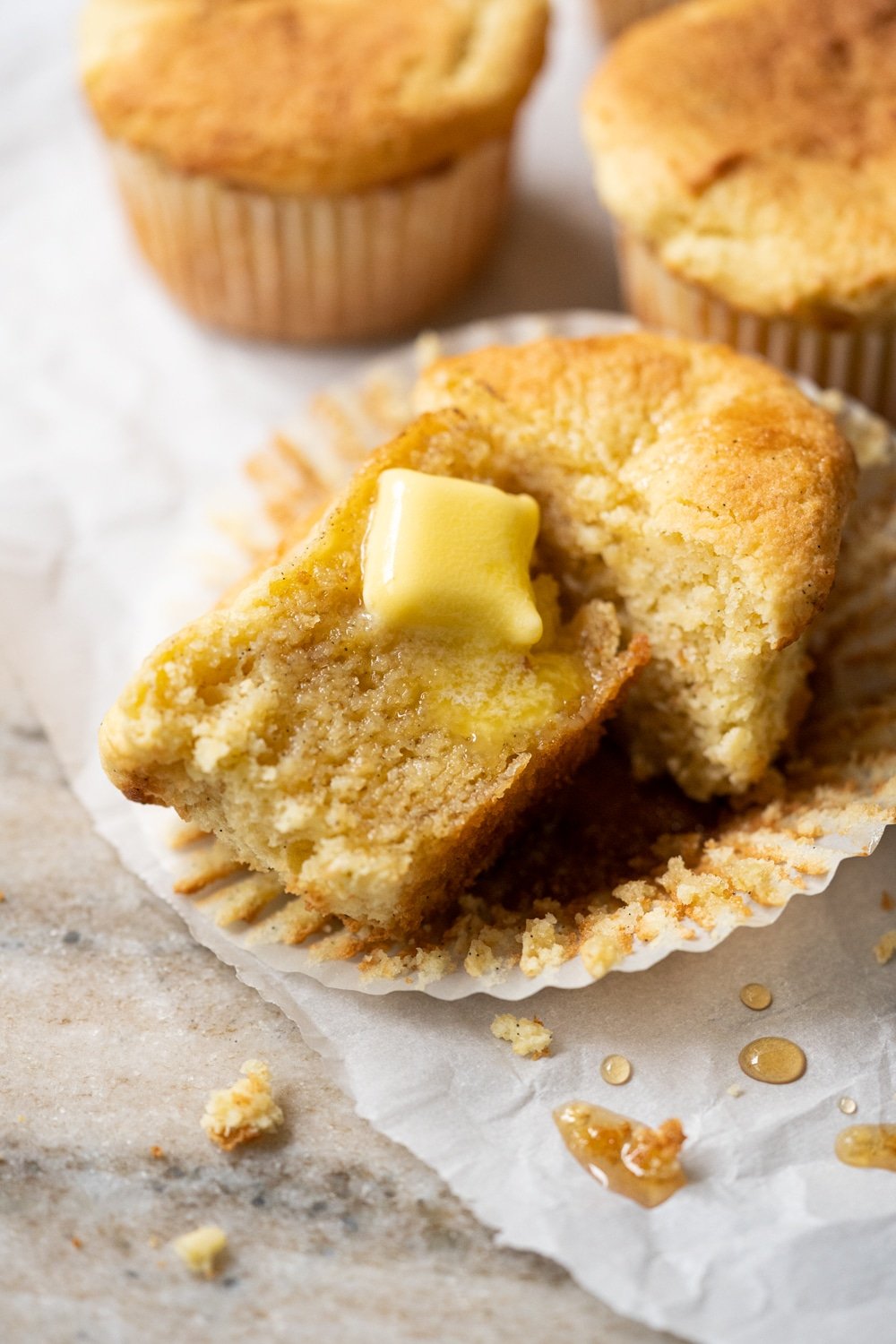 A halved keto cornbread muffin with a pat of butter melting through