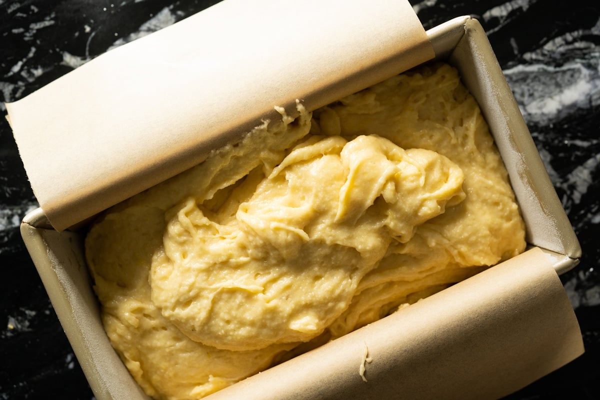 Pouring the thick grain free lemon pound cake batter onto a lined loaf pan