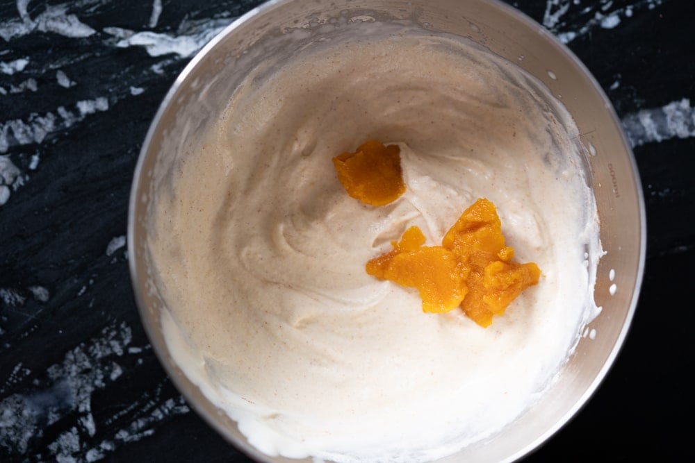 Adding pumpkin puree to a bowl with very lightly whipped cream