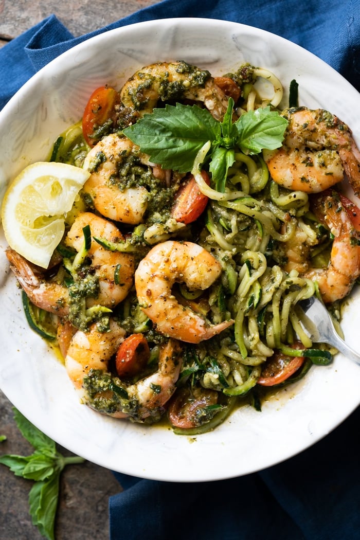 Keto zoodles with shrimp, pesto and lemon in a white bowl