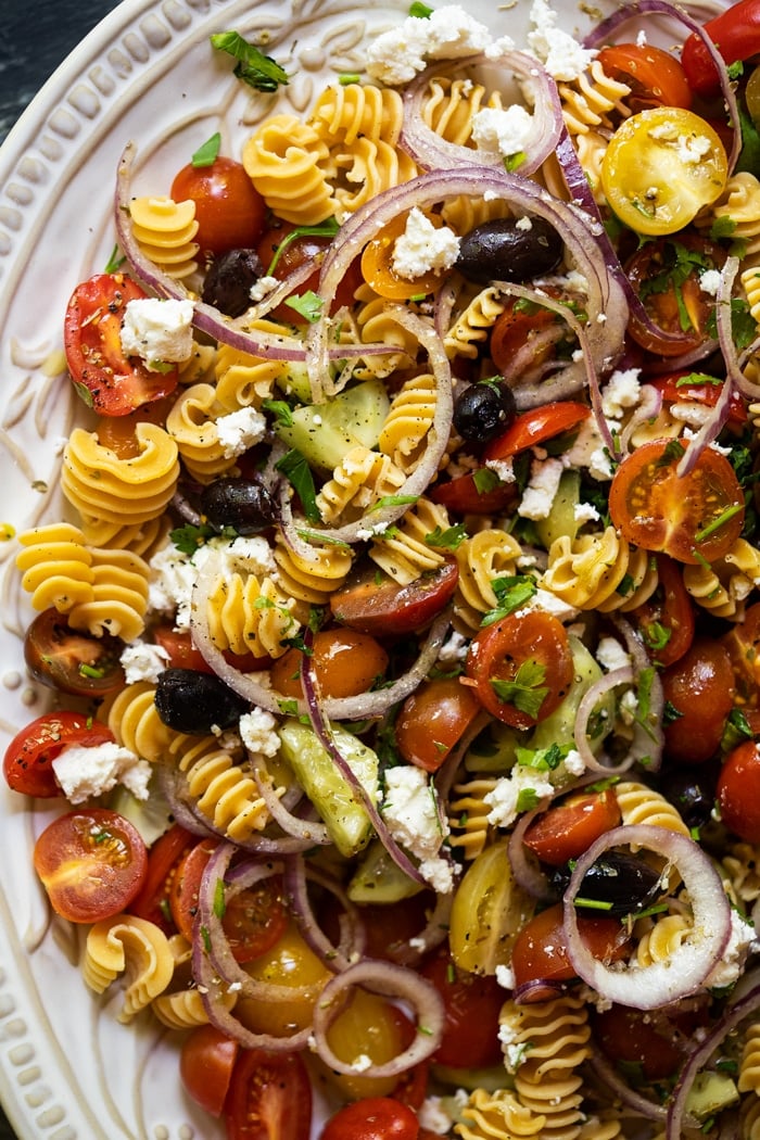 Keto pasta salad with cherry tomatoes, cucumber and olives on a white serving platter