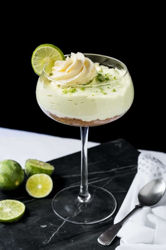 Keto key lime cheesecake in a glass with scattered limes