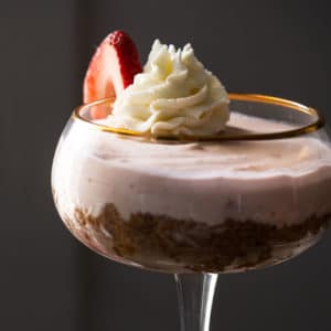 Keto strawberry cheesecake in a tall glass with whipped cream