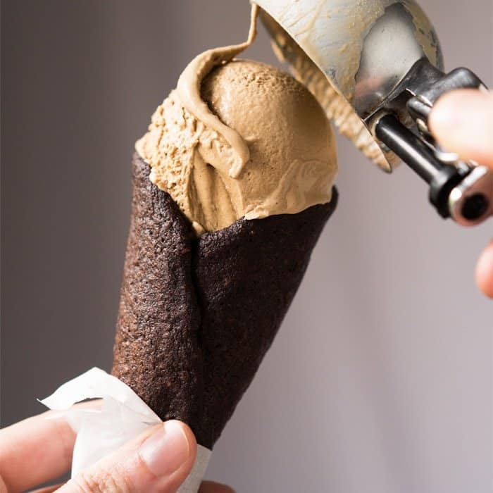 Scooping keto ice cream onto a chocolate cone