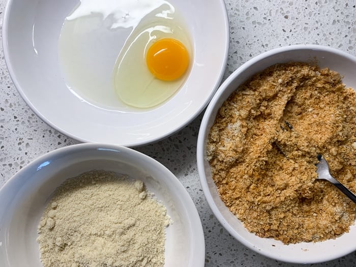 Three bowls with an egg, almond flour and the paleo and keto breading
