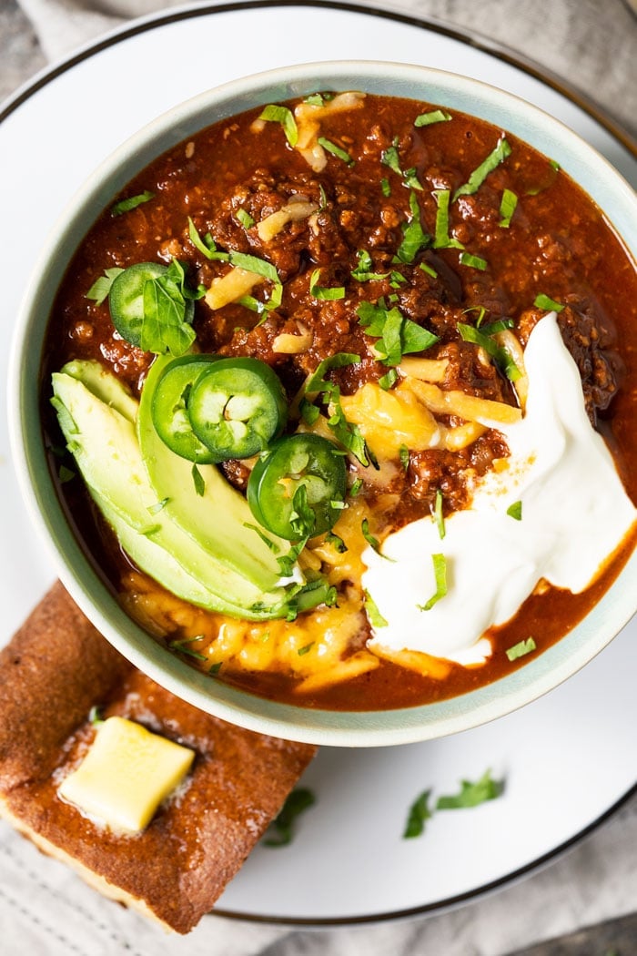 Bowl of keto chili with cornbread and toppings
