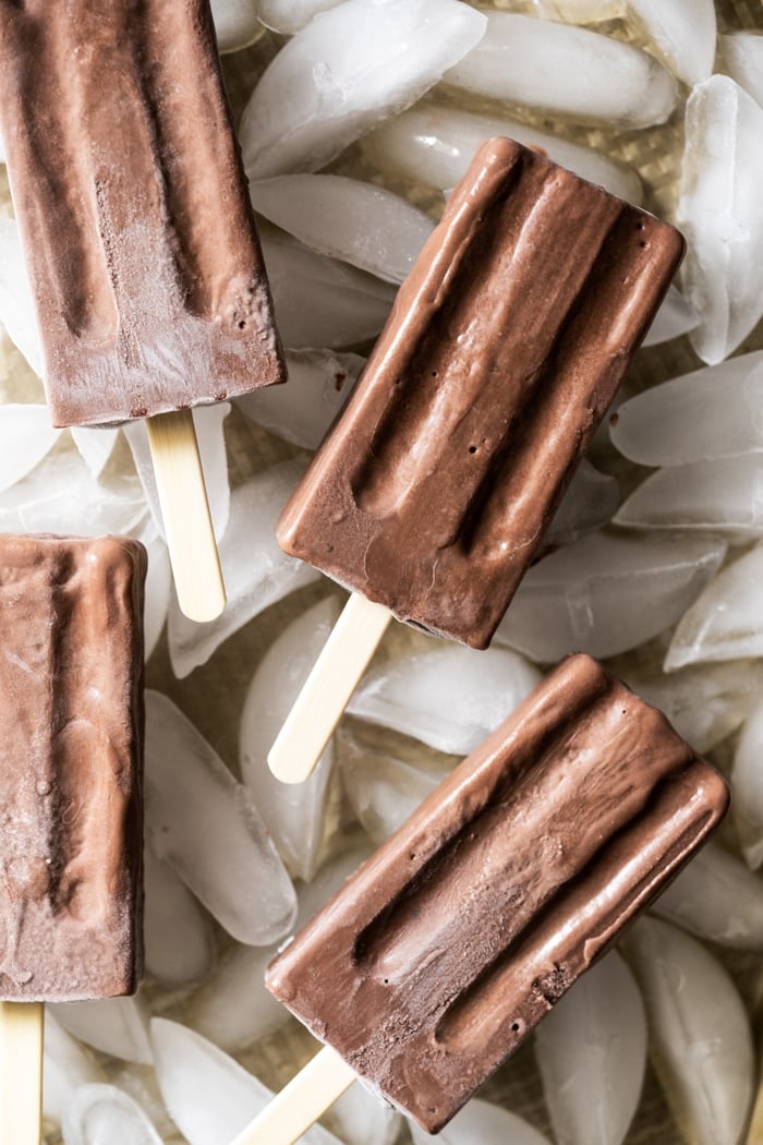 Freshly unfolded chocolate popsicles on a bed of ice