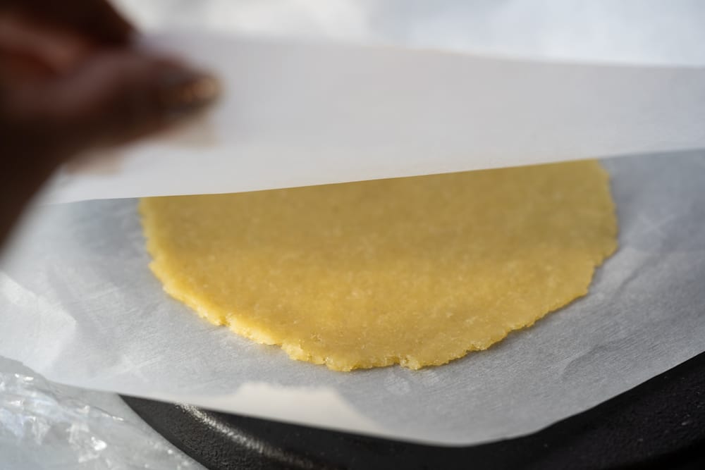 A piece of almond cereal dough pressed down using a tortilla press