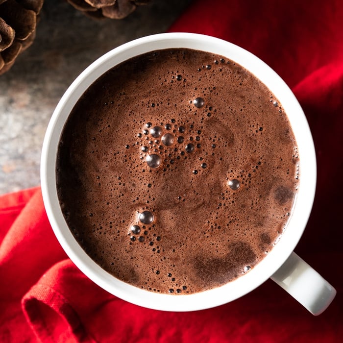 Creamy keto hot chocolate in a white mug over a red napkin