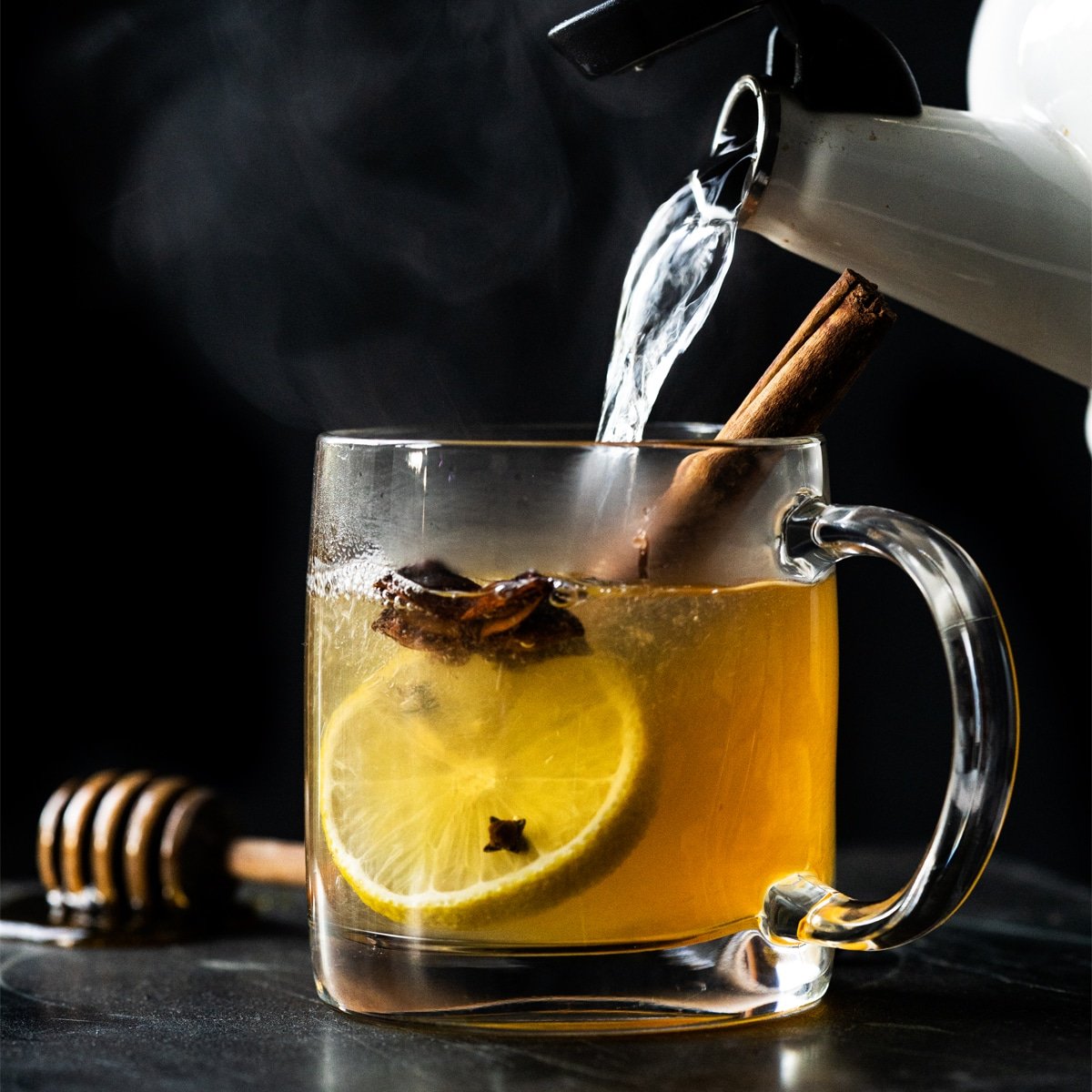 Pouring hot water into a paleo and keto hot toddy with lemon, star anise and a cinnamon stick