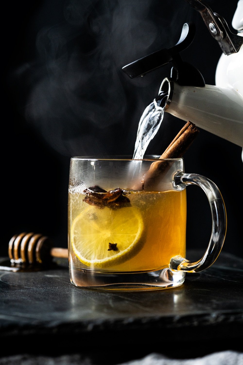 Pouring hot water into a paleo and keto hot toddy with lemon, star anise and a cinnamon stick