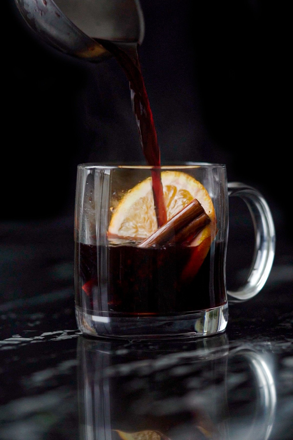 Pouring keto mulled wine onto a mug with an orange slice, cinnamon stick and star anise