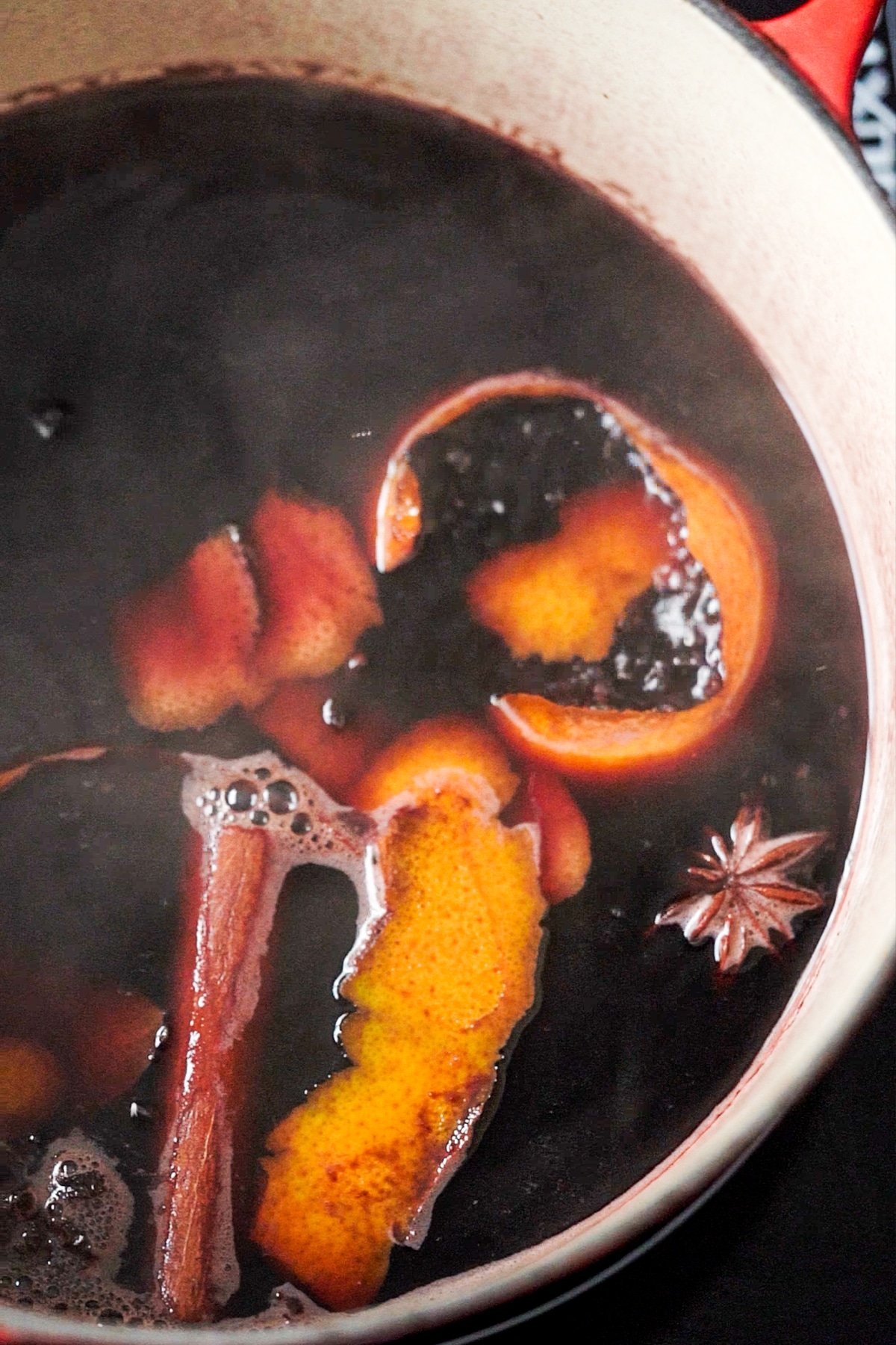 Simmering keto mulled wine in a dutch oven with cinnamon, star anise, orange, cloves and cinnamon
