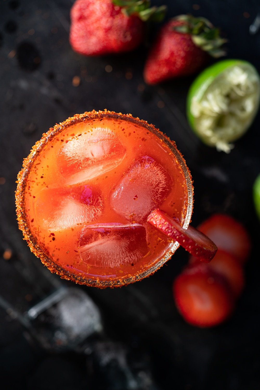 Overhead shot of a keto strawberry margarita with limes and strawberries scattered around it