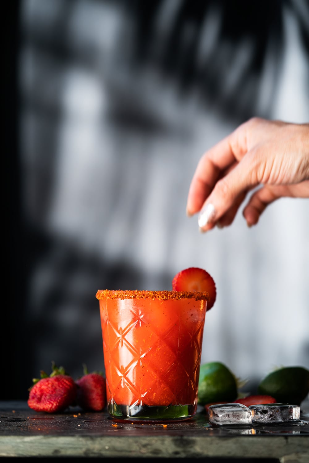 Placing a strawberry slice on the rim of a paleo strawberry margarita