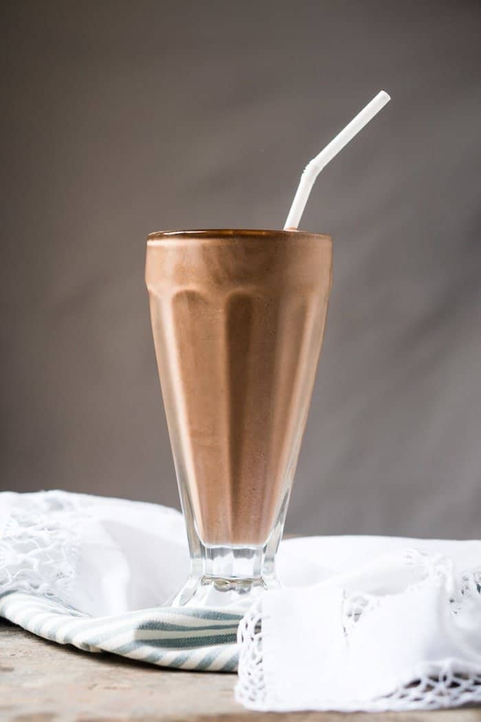 A paleo and keto chocolate milkshake in a tall glass with a straw