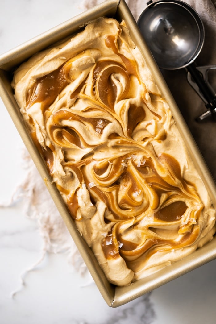 Keto caramel ice cream with caramel swirls in a gold container